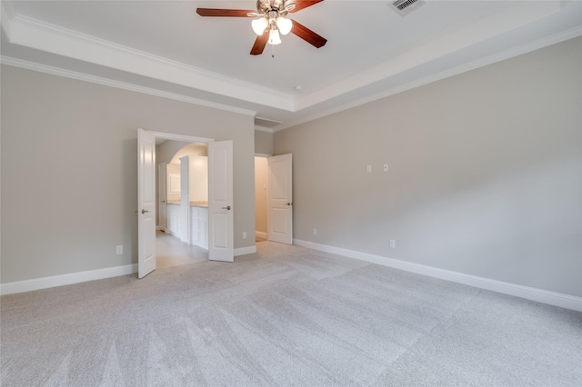 unfurnished bedroom featuring ornamental molding, light colored carpet, ceiling fan, and a tray ceiling