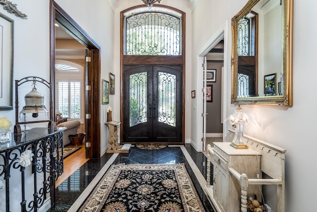 foyer entrance featuring french doors, crown molding, and a high ceiling