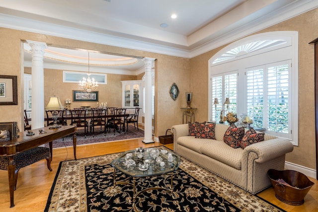 living room with a tray ceiling, ornamental molding, light hardwood / wood-style floors, and decorative columns