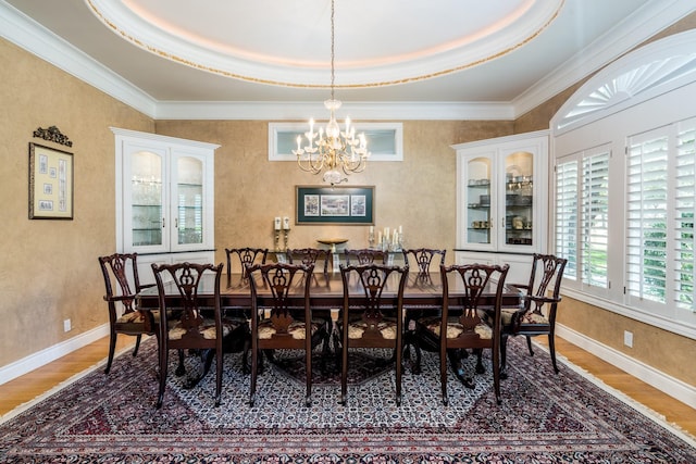 dining room with a tray ceiling, ornamental molding, dark hardwood / wood-style floors, and a chandelier