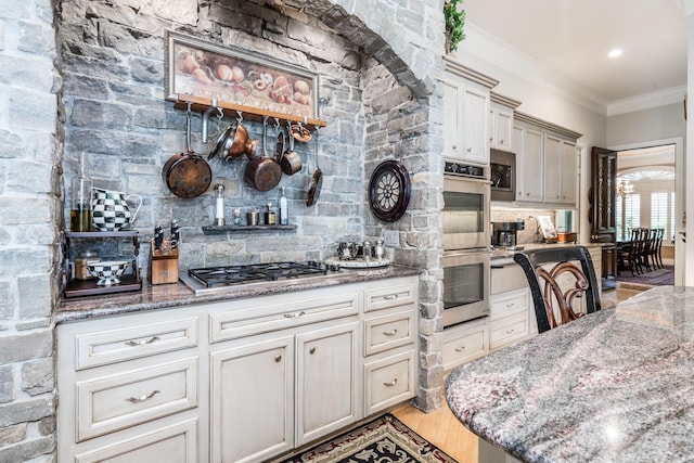 kitchen with stone counters, crown molding, appliances with stainless steel finishes, and light hardwood / wood-style floors