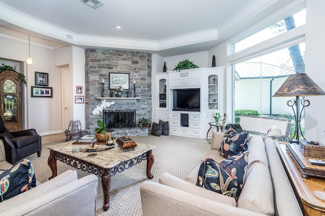 living room with crown molding, a tray ceiling, and a fireplace