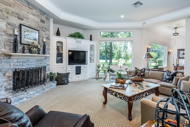 living room with a fireplace, ornamental molding, light colored carpet, ceiling fan, and a raised ceiling