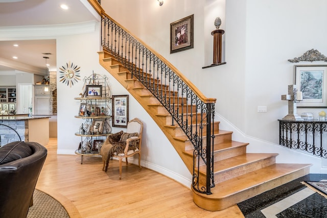 stairway with hardwood / wood-style flooring and crown molding