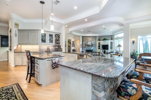 kitchen with a kitchen bar, tasteful backsplash, hanging light fixtures, a large island with sink, and stainless steel dishwasher