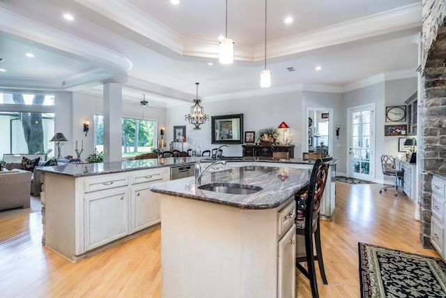 kitchen featuring an island with sink, dark stone countertops, pendant lighting, and a kitchen bar