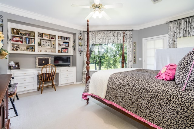 carpeted bedroom featuring built in desk, ornamental molding, and ceiling fan