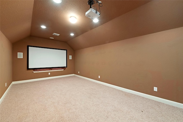 cinema with vaulted ceiling, carpet floors, and a textured ceiling