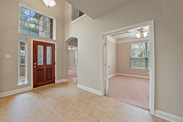 foyer with crown molding, light colored carpet, and ceiling fan