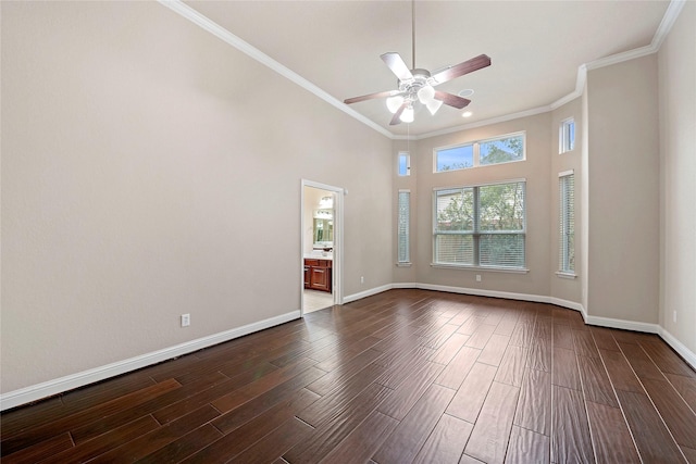 empty room featuring dark hardwood / wood-style flooring, crown molding, ceiling fan, and a towering ceiling