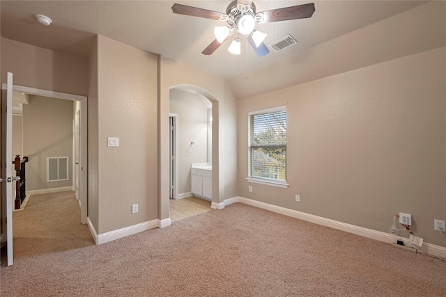 unfurnished bedroom with connected bathroom, light colored carpet, and ceiling fan