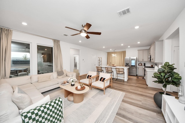 living room with ceiling fan and light wood-type flooring