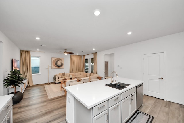 kitchen with sink, a kitchen island with sink, a wealth of natural light, light hardwood / wood-style floors, and stainless steel dishwasher