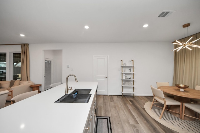 kitchen featuring hanging light fixtures, a notable chandelier, light hardwood / wood-style floors, and sink