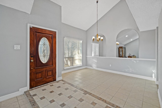 entryway with light tile patterned flooring, vaulted ceiling, a notable chandelier, and a textured ceiling