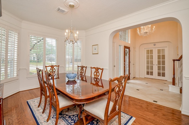 dining space featuring an inviting chandelier, crown molding, french doors, and hardwood / wood-style flooring