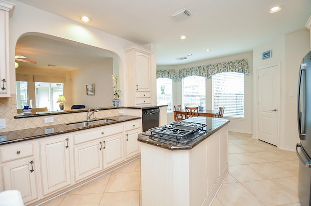 kitchen with sink, tasteful backsplash, a center island, appliances with stainless steel finishes, and dark stone counters