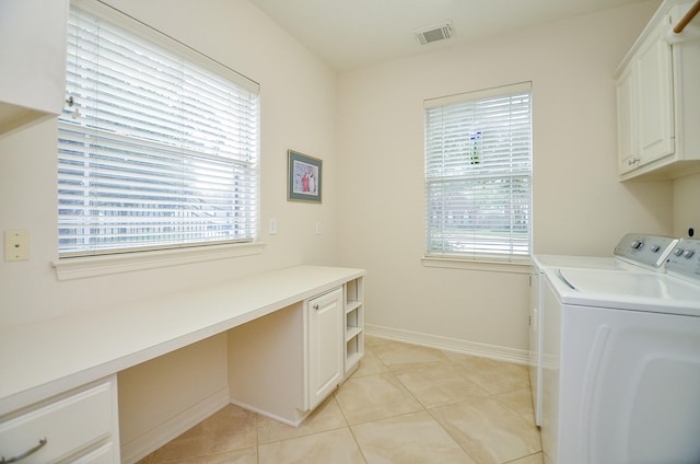 clothes washing area with cabinets, a healthy amount of sunlight, light tile patterned floors, and washer and clothes dryer