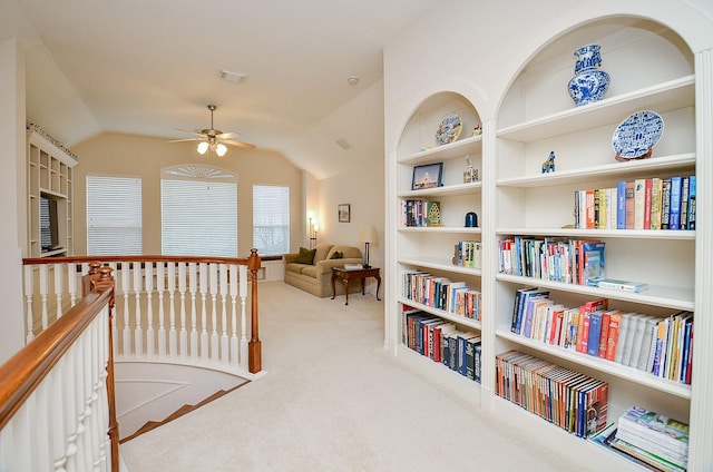 sitting room with vaulted ceiling, light colored carpet, ceiling fan, and built in shelves