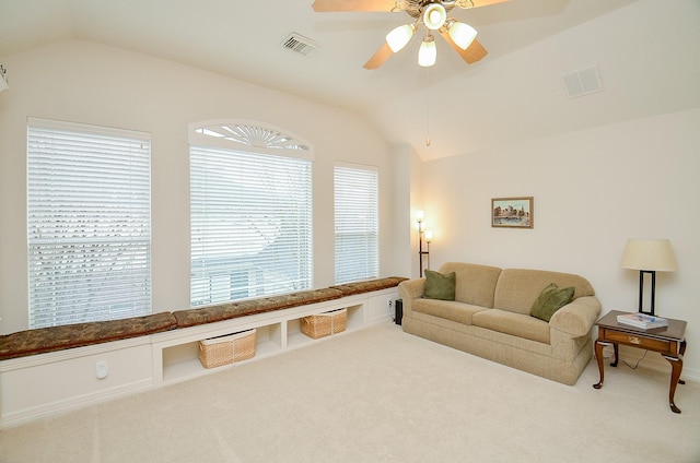 carpeted living room with ceiling fan and vaulted ceiling