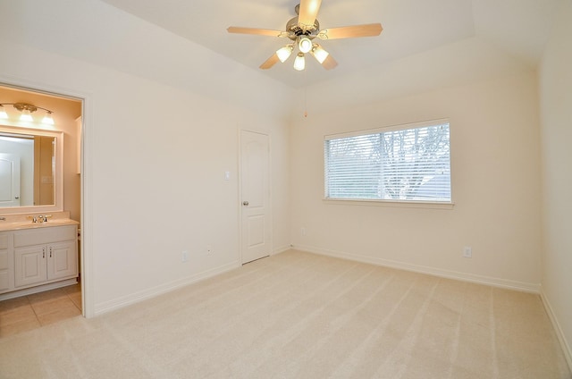 unfurnished bedroom with light colored carpet, ensuite bathroom, a tray ceiling, and sink