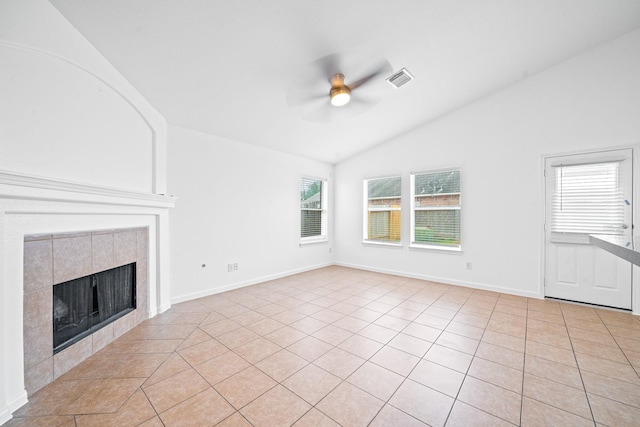 unfurnished living room with lofted ceiling, light tile patterned floors, a tile fireplace, and a healthy amount of sunlight