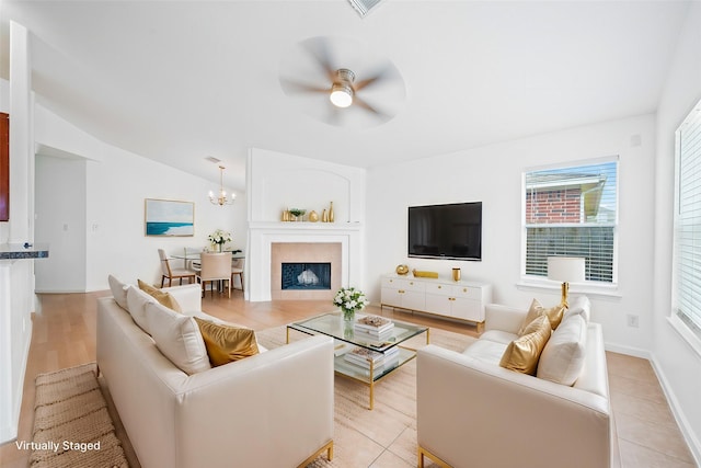 living room with vaulted ceiling, ceiling fan with notable chandelier, and light hardwood / wood-style flooring