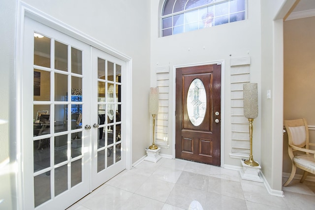 entrance foyer featuring light tile patterned floors, crown molding, a wealth of natural light, and french doors