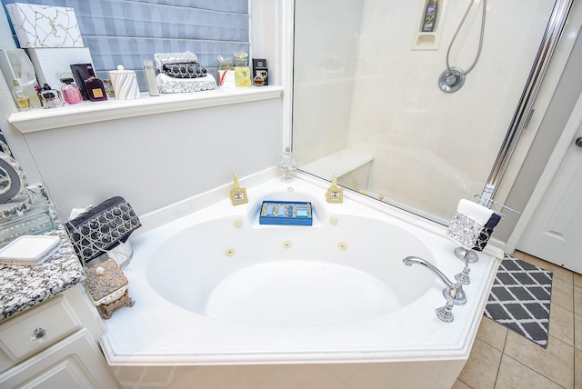 bathroom with tiled tub, vanity, and tile patterned floors