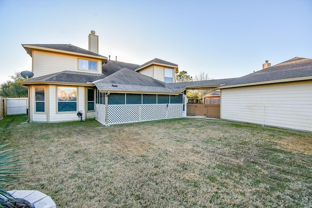 back of property with a lawn and a sunroom