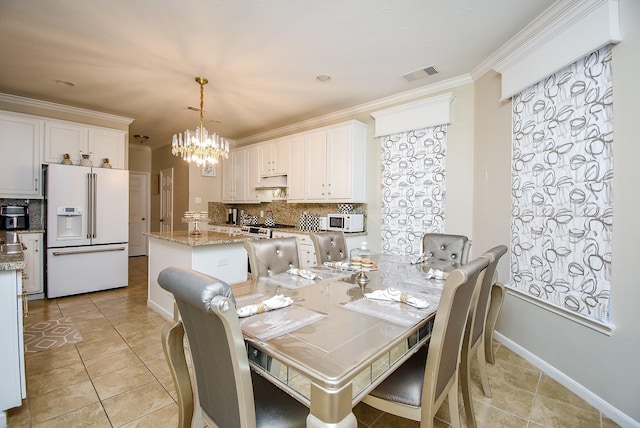 tiled dining space featuring ornamental molding and an inviting chandelier