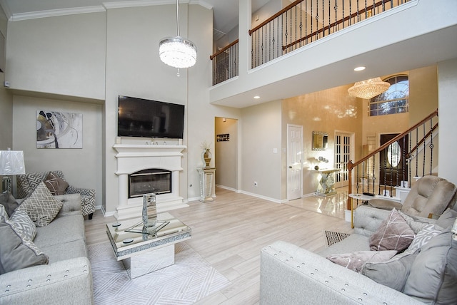 living room with crown molding, a towering ceiling, hardwood / wood-style floors, and a notable chandelier