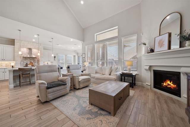 living room with ornamental molding, high vaulted ceiling, and light wood-type flooring