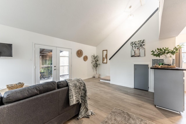 living room featuring lofted ceiling, light hardwood / wood-style flooring, and french doors