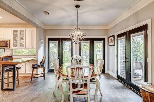 dining room with crown molding, light wood-type flooring, and french doors