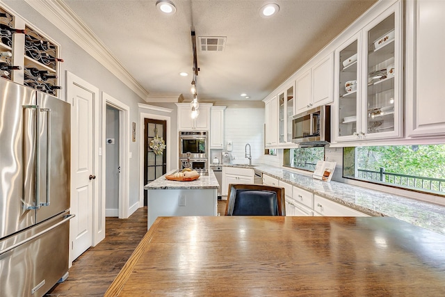 kitchen with pendant lighting, white cabinetry, ornamental molding, a center island, and stainless steel appliances