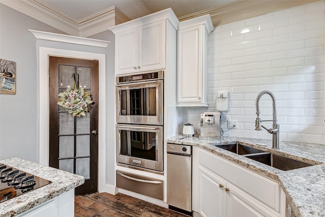 kitchen featuring sink, white cabinetry, ornamental molding, stainless steel double oven, and black stovetop