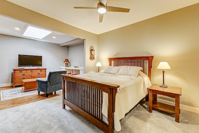 bedroom featuring ceiling fan, a skylight, and light hardwood / wood-style flooring