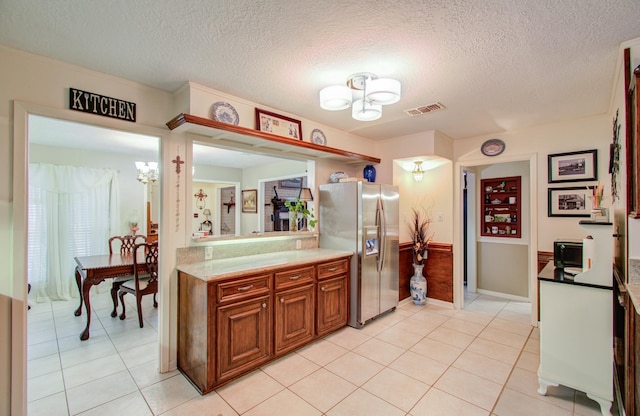 kitchen featuring light tile patterned flooring, a textured ceiling, stainless steel fridge, and an inviting chandelier