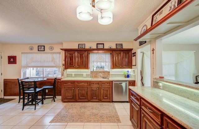 kitchen with sink, stainless steel dishwasher, a textured ceiling, and light tile patterned floors