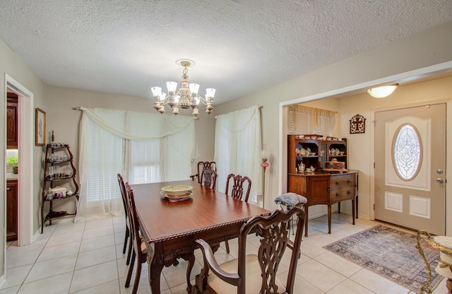 dining area featuring light tile patterned flooring, a textured ceiling, and a notable chandelier