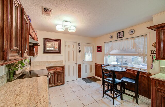 kitchen featuring light tile patterned floors, light stone countertops, range with electric cooktop, and a textured ceiling