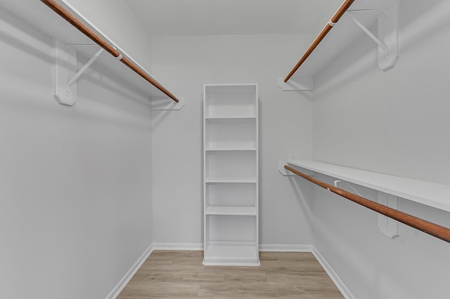 walk in closet with light hardwood / wood-style floors