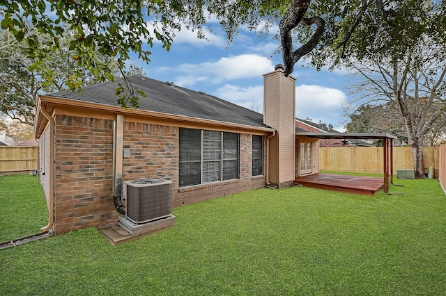 rear view of property with a yard, cooling unit, and a deck