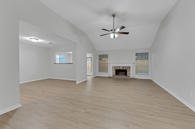 unfurnished living room with ceiling fan, lofted ceiling, a fireplace, and light wood-type flooring