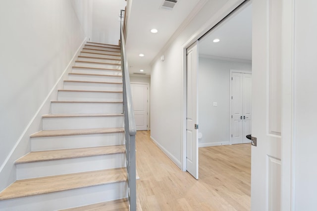 stairs featuring wood-type flooring and crown molding