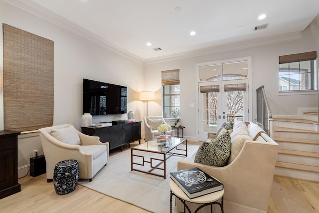 living room with ornamental molding, french doors, and light wood-type flooring