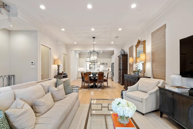 living room with ornamental molding, a chandelier, and light hardwood / wood-style floors