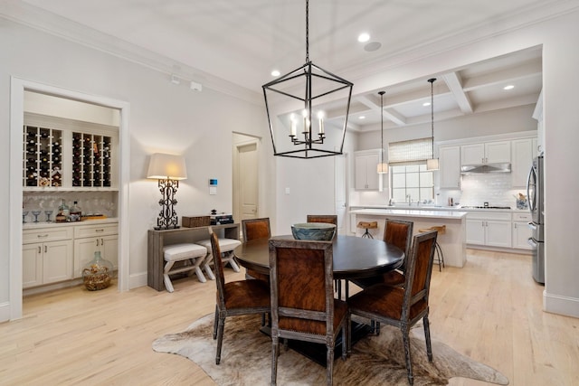 dining space with ornamental molding, coffered ceiling, beam ceiling, and light hardwood / wood-style flooring