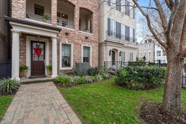 view of exterior entry featuring a balcony and a lawn